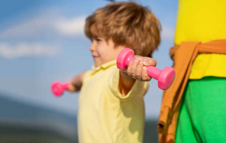 Sporty boy with dumbbells. Sport. Fitness, health and energy. Cheerful boy do exercises with dumbbells. Healthy lifestyle. Fitness child. Kid exercising with dumbbells. Sport for little childrenの写真素材