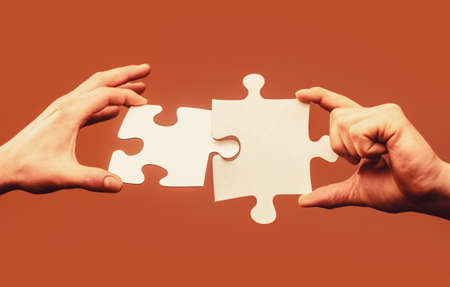 Closeup hands of man connecting jigsaw puzzle. Business solutions, success and strategy concept. Two...