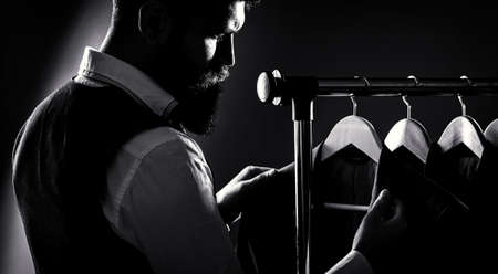 Mens suit, tailor in his workshop. bearded fashion man in classical costume suit. Male hanging in a...