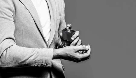 Man holding up bottle of perfume. Men perfume in the hand on suit background. Man in formal suit,...