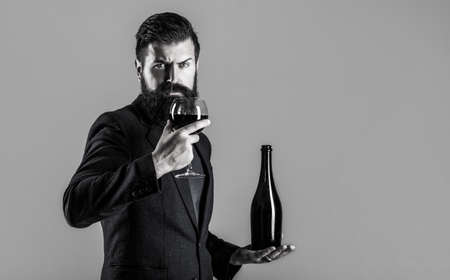 Red wine in bottle, wine glass. Red wine in a glass. Man holding bottle with champagne, wine. Beard man, bearded, sommelier, tasting. Sommelier man, degustator, winery. Black and whiteの写真素材