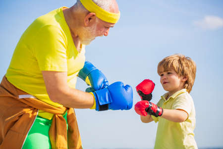 Little boy doing boxing exercise with grandfather. Father is training his son boxing. Little boy...