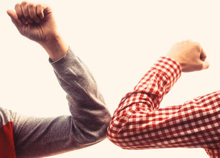 Friends shaking elbows outdoors. Coronavirus epidemic. Closeup elbow bump. Couple greeting with elbows. Elbows bumpの写真素材