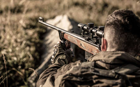 The man is on the hunt. Hunt hunting rifle. Hunter man. Hunter with hunting gun and hunting form to hunt. Hunter is aiming. Shooter sighting in the targetの写真素材