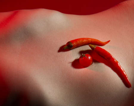 Chili pepper. Red peppers, seasoning paprika, red pepper on stomach, belly, abdomen. Dish of red pepper. Hot girl, sexy bellyの写真素材