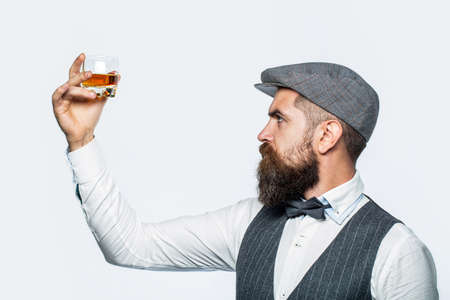 Bearded gentleman drink cognac. Sipping finest whiskey. Portrait of man with thick beard. Macho drinking. Stylish rich man holding a glass of old whiskyの写真素材