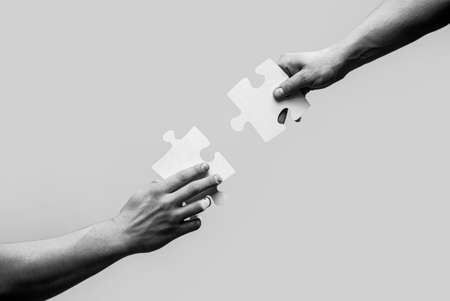 Two hands trying to connect couple puzzle. Closeup hands of man connecting jigsaw puzzle. Business...