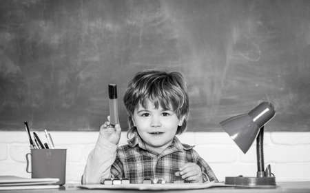 Preschooler near the blackboard. Young student. Education and children. Happy smiling pupil drawing...