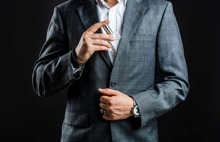 Male holding up bottle perfume. Hand in with wrist watch in a business suit. Perfume or cologne bottle and perfumery, cosmetics, scent cologne bottle, male holding cologneの写真素材