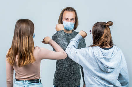 Friends wearing face mask doing new social distancing greet with elbows bumps for preventing corona virus spread - Physical distance and friendship safety greetings conceptの写真素材
