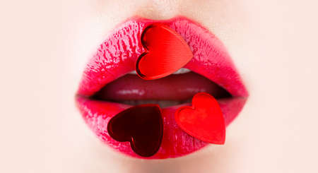 Valentines Day. Beautiful love, mak-eup. Red heart on lips, Valentines Day. Valentine lip. Gloss red heart lip. Valentine heart, kiss on the lips. Makeup, beauty sexy lips with heartの写真素材