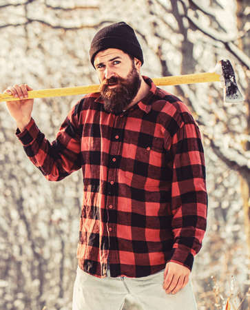 Bearded lumberjack. Brutal bearded lumberjack with ax in winter forest. Handsome man, hipster in snowy forest. Lumberjack with an ax in his hands. Male holds an ax on a shoulder. Brutal bearded manの写真素材