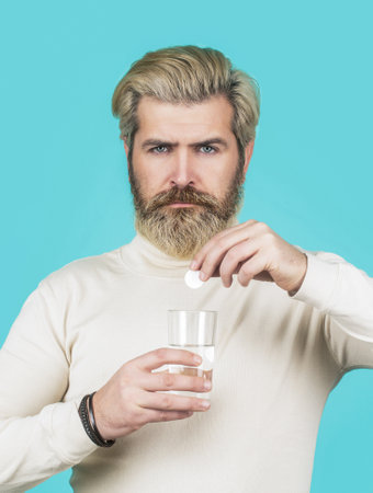 Man taking pill against headache. Male taking a pill with a glass of water. Man take some pills,...