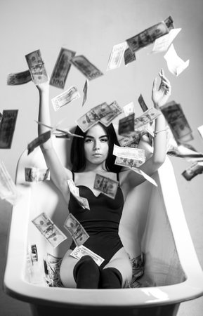 Sexy female and dollar bills. Woman with lot of money. Millionaire woman lying in bedroom. Sexy woman lying in dollar bills. Black and whiteの写真素材