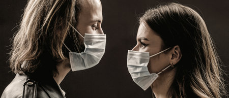 Faces of people in protective masks from coronavirus. Beautiful quarantined couple. Couple wearing a protective face mask, pandemic and feelings concept. Lifestyle COVID-19の写真素材