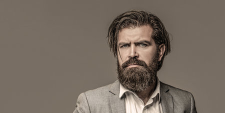 Male beard and mustache. Handsome stylish bearded man. Bearded man in suit and bow-tie. Sexy male, macho, long beard. Studio portrait of a bearded hipster manの写真素材