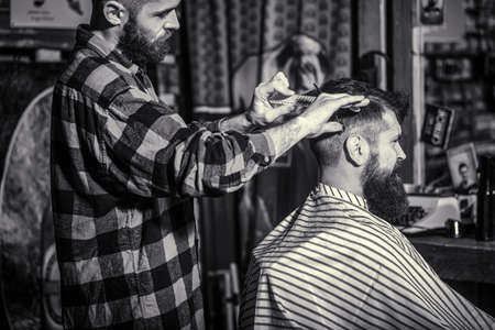 Man visiting hairstylist in barbershop. Barber scissors. Black and white. Bearded man in barber shopの写真素材