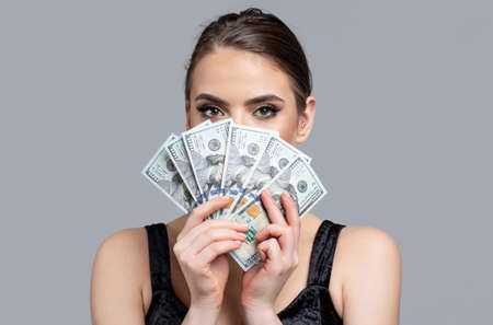 Woman with dollars in hand. Portrait woman holding money banknotes. Girl holding cash money in dollar banknotes. Woman holding lots of money in dollar currency. Luxury, beauty and money conceptの写真素材