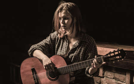 Woman playing guitar, holding an acoustic guitar in his hands. Music concept. Girl guitarist plays. Girl play the guitar. Woman hipster man sitting in a pubの写真素材
