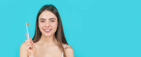 Smiling woman with healthy teeth holding a tooth brush. Young beautiful girl holding a toothbrush....