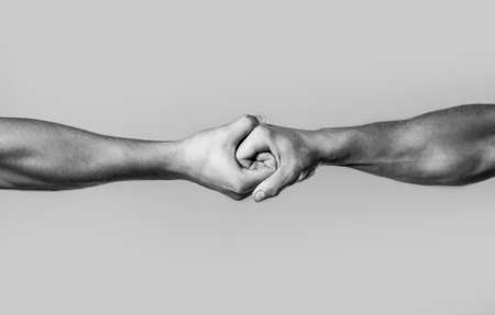 Male hand united in handshake. Man help hands, guardianship, protection. Two hands, isolated arm, helping hand of a friend. Friendly handshake, friends greeting. Rescue, helping hand. Black and whiteの写真素材