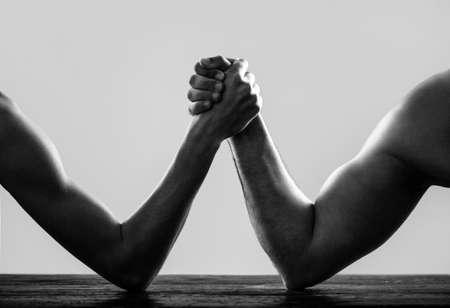 Arms wrestling thin hand and a big strong arm in studio. Arm wrestling. Heavily muscled man arm...