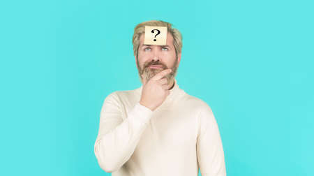 Man with question mark on forehead looking up. Paper notes with question marks. Beard man question...