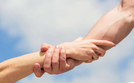 Giving a helping hand. Hands of man and woman on blue sky background. Lending a helping hand. Hands...
