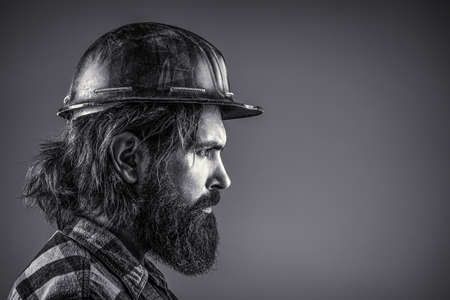 Building, industry, technology - builder concept. Bearded man worker with beard in building helmet or hard hat. Black and whiteの写真素材