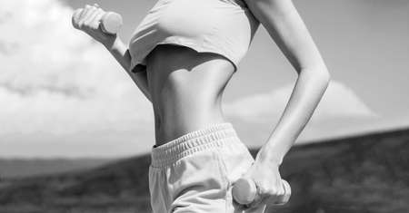 Sports fitness sexy girl, dumbbells. Woman with dumbbell fit slim abs body. Fit female exercising muscles. Sexy body, fitness. Black and whiteの写真素材
