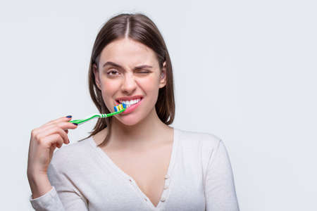 Portrait of a smiling cute woman holding toothbrush. Smiling woman with healthy beautiful teeth holding a toothbrush. Dental health background. Close up of perfect and healthy teeth with toothbrushの写真素材