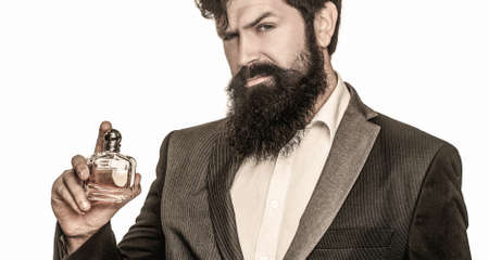 Perfume or cologne bottle and perfumery, cosmetics, scent cologne bottle, male holding cologne. Masculine perfume, bearded man in a suit. Male holding up bottle of perfumeの写真素材