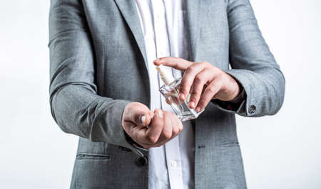 Perfume or cologne bottle and perfumery, cosmetics, scent cologne bottle, male holding cologne. Masculine perfume, bearded man in a suit. Male holding up bottle of perfume. Man perfume, fragranceの写真素材
