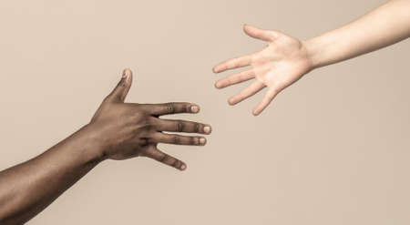 Helping hand, Rescue, multiathnic people. Helping hands, Rescue gesture. Black and white human hands. African and caucasian hands. Giving a helping hand to another. Woman and african woman handの写真素材