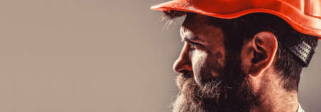 Building, industry, technology - builder concept. Bearded man worker with beard in building helmet...