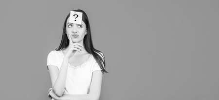 Thinking woman with question mark. Doubtful girl asking questions to himself. Paper notes with question marks. Confused female thinking with question mark on sticky note on foreheadの写真素材
