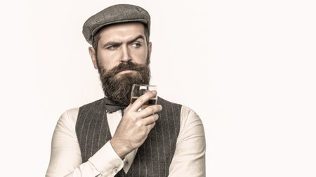Sipping finest whiskey. Portrait of man with thick beard. Macho drinking. Stylish rich man holding a glass of old whisky. Bearded gentleman drink cognacの写真素材