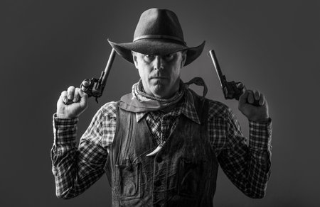 Man wearing cowboy hat, gun. Portrait of a cowboy. West, guns. Portrait of a cowboy. Western man with hat. Portrait of farmer or cowboy in hatの写真素材