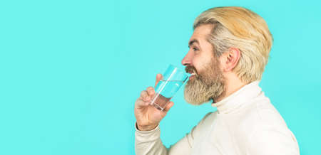 Bearded man drinking water. Happy beard man drinking water. Male drinking from a glass of water. Health care concept, lifestyle, close up. Smiling male holding transparent glass in her handの写真素材