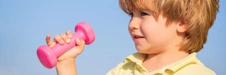 Fitness child. Sporty boy with dumbbells. Fitness, health and energy. Cheerful boy do exercises with dumbbells. Kid exercising with dumbbells. Sport for little children. Healthy lifestyleの写真素材