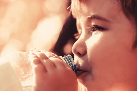Boy bottle of water. Young boy holding drink fresh water bottle. A child drinks water from a bottle while walking, baby healthの写真素材
