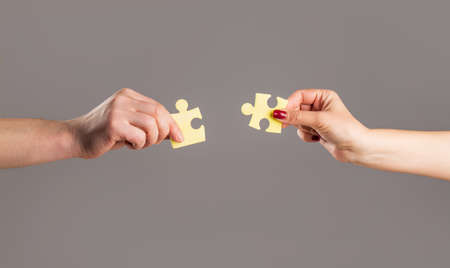 Hands hold puzzles. Solution of problems. Mens and childs hands connecting puzzles. Hands connecting puzzle. Puzzles. Hand of the child and hand of mother fold puzzle, closeupの写真素材