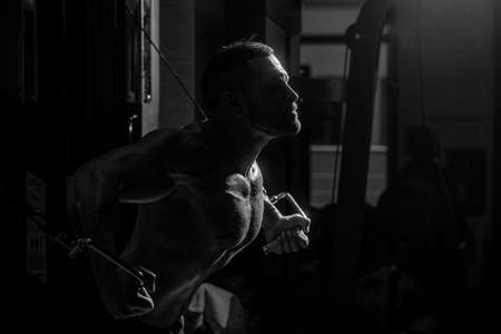 Muscular man workout in gym doing exercises for chest, cable crossover. Strong male torso abs. Fitness man execute exercise with exercise-machine Cable Crossover in gym. Man with big muscles in gymの写真素材