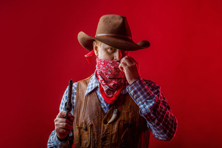 American bandit in mask, western man with hat. Portrait of man wearing cowboy hat, gun, macho. West, guns. Portrait of farmer or cowboy in hat. Portrait of a cowboy.の写真素材