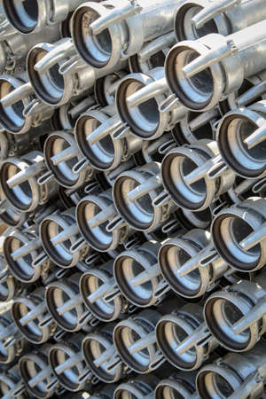 Several piled up irrigation pipes with clamps