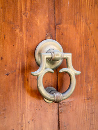 An antique brass metal knocker on a wooden doorの写真素材