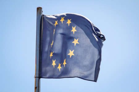 A euro flag flutters in the wind against a blue skyの写真素材