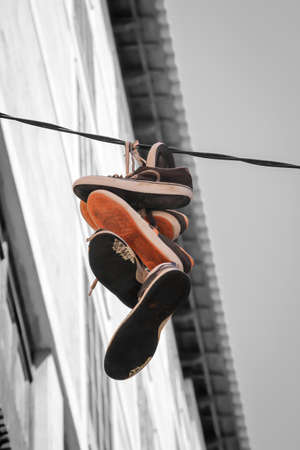 Several pairs of shoes tied together hang on a power lineの写真素材