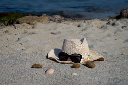 Decoration of a sun hat with sunglasses and seashells on the beach. Summer decoration.の写真素材