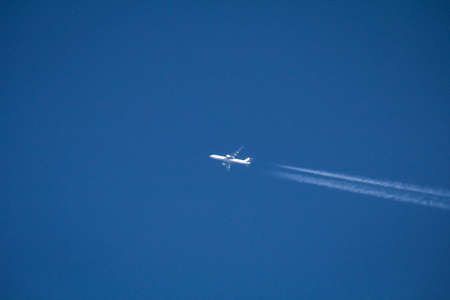 A passenger jet, airplane, leaves white contrails in the sky.